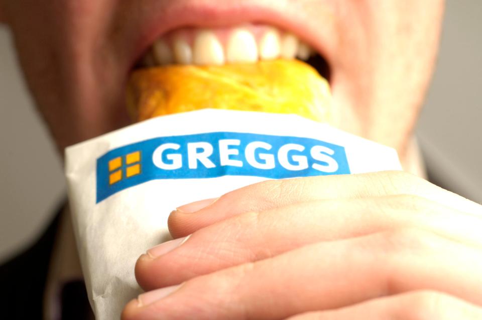 EDBJ1T A man enjoying his recently purchased Greggs sausage roll.