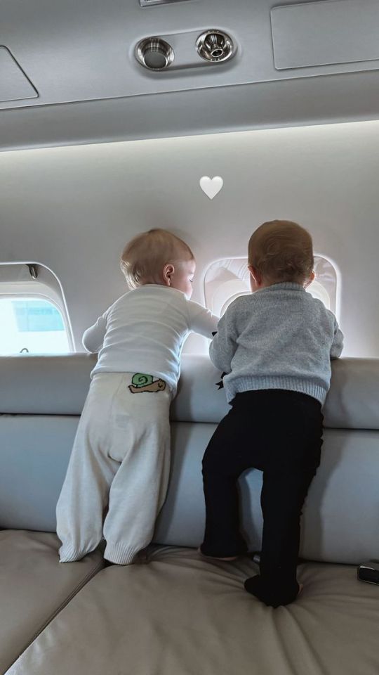 two babies are looking out of an airplane window