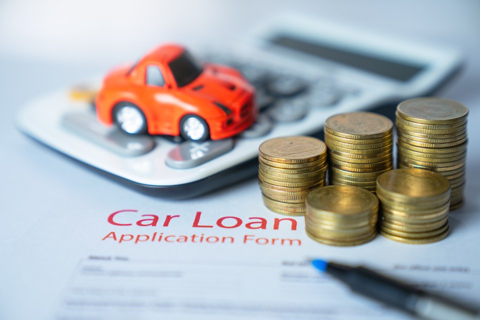 Car loan application form with coins and toy car.