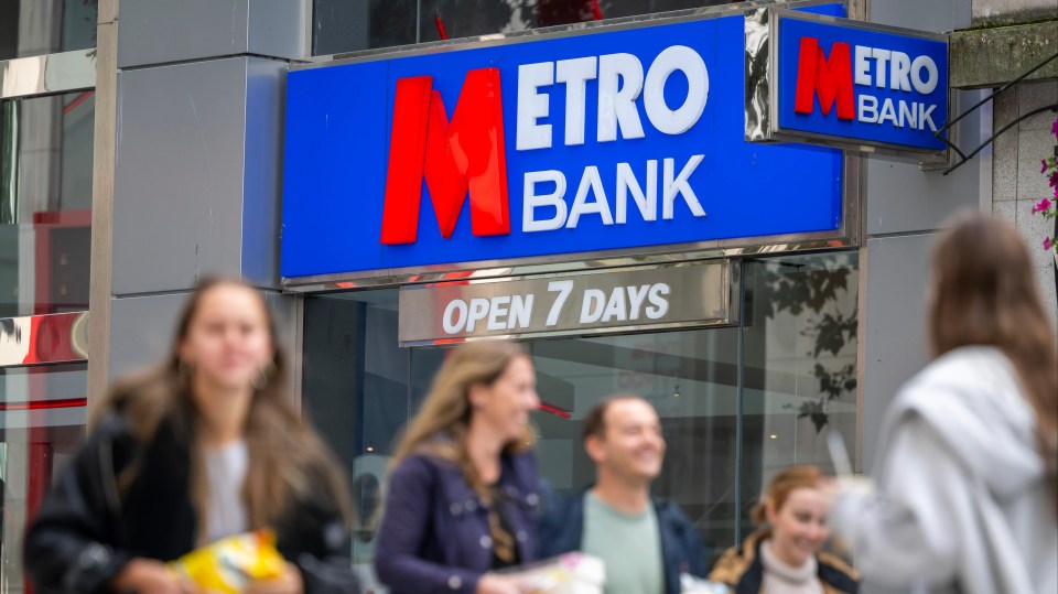 people walking in front of a metro bank that is open 7 days a week