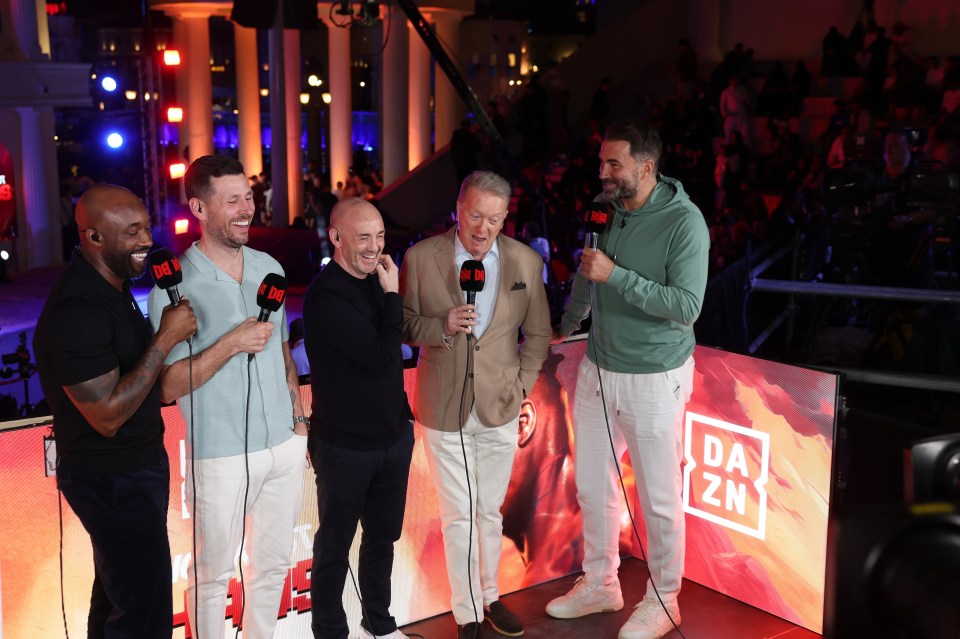 a group of men standing in front of a dazn sign