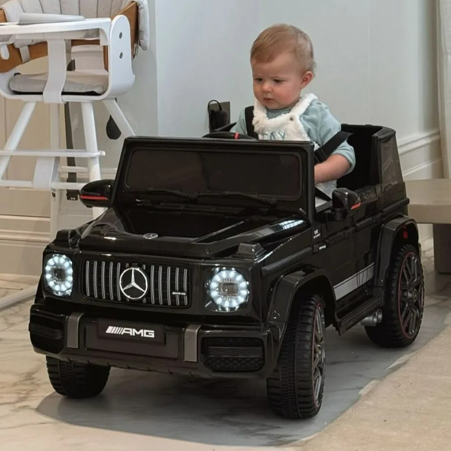 a baby is sitting in a black amg toy car