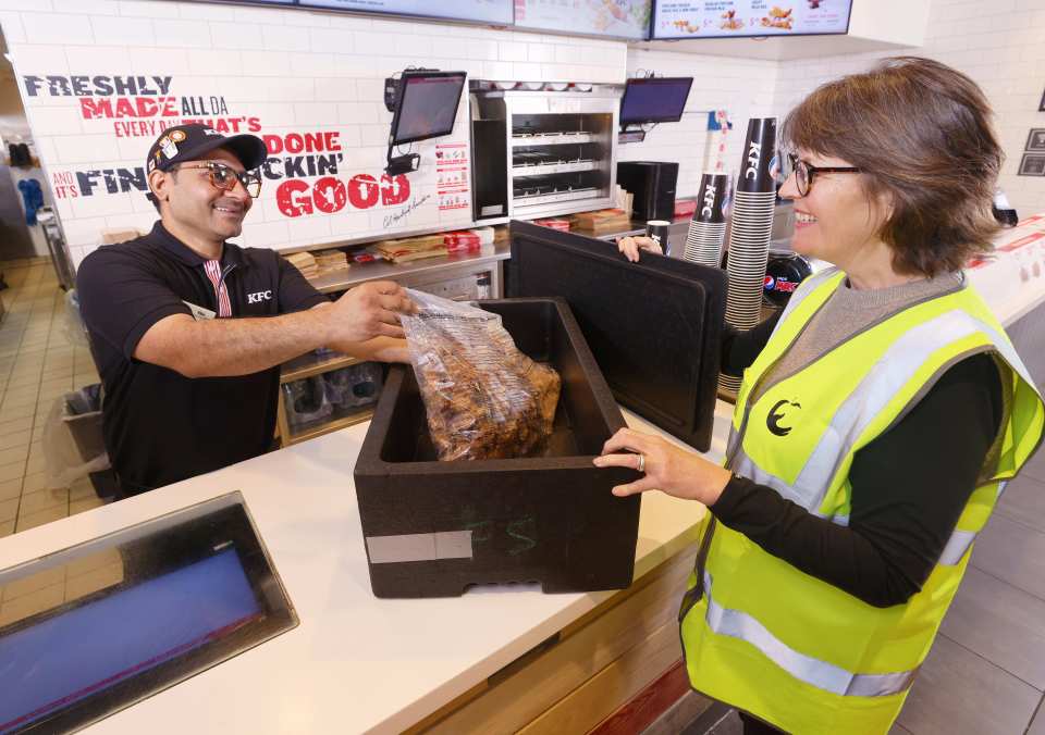 KFC restaurant manager Vikas Nara hands over redistributed KFC chicken to FareShare volunteer Jo Hyne