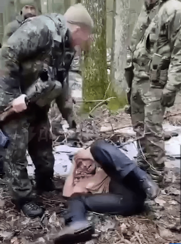 One of the terror suspects cowering on the ground as Russian soldiers brutally hit him