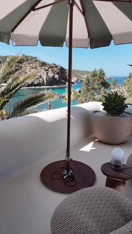 a green and white striped umbrella sits on a balcony overlooking the ocean