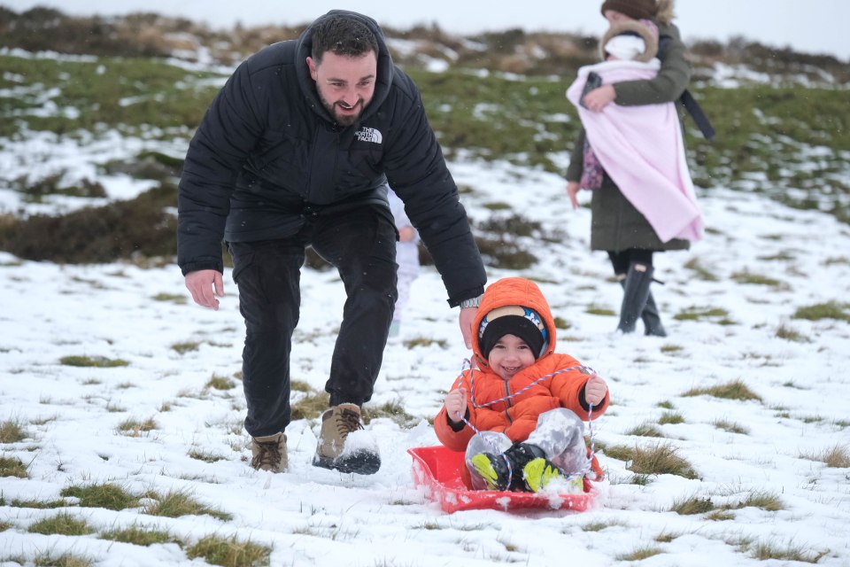 Jack Campbell pushes his son Harvey on a sledge in the snow on Dartmoor yesterday