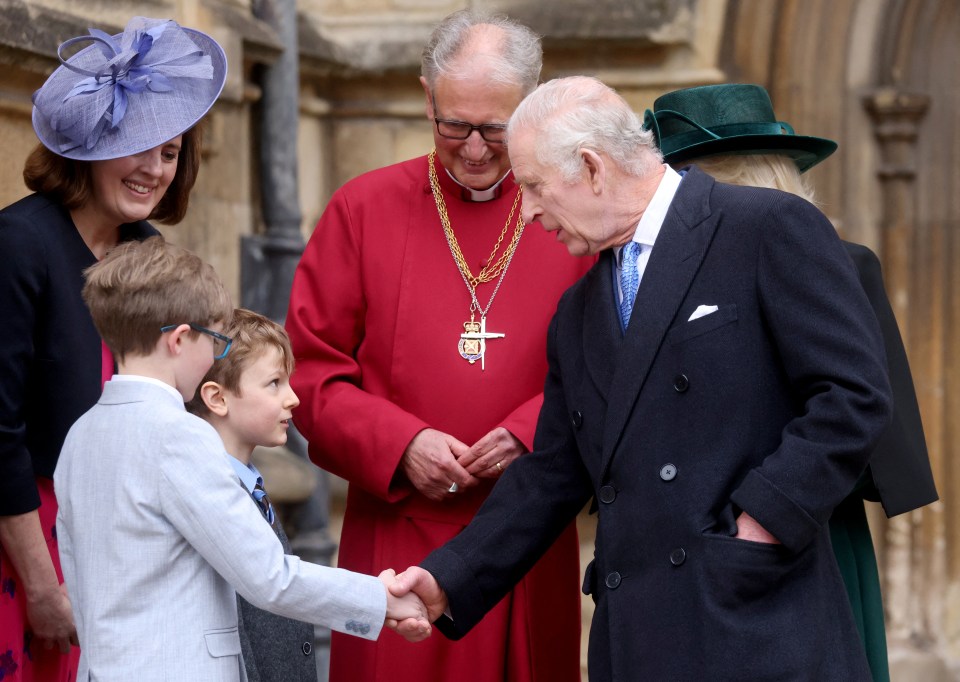 The King shakes a boy's hand outside St George's Chapel at Windsor