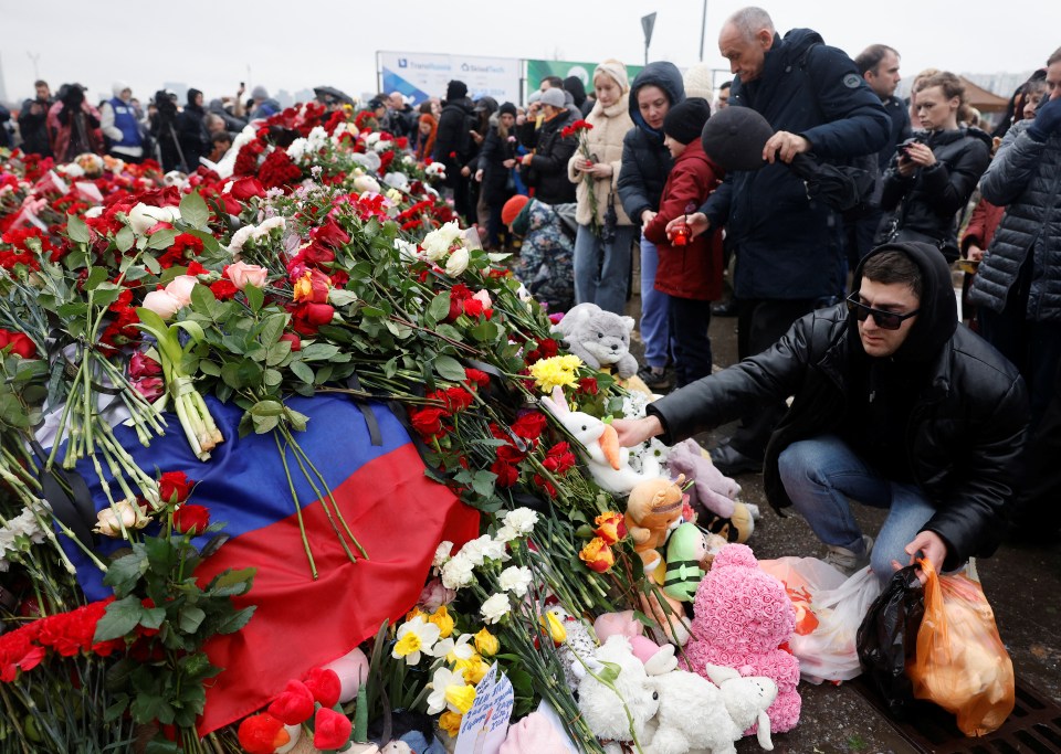 A man puts a toy at a makeshift memorial to the victims of a shooting attack set up outside the Crocus City Hall concert venue