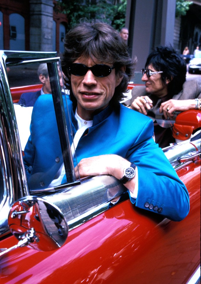 Mick Jagger and Ron Wood of The Rolling Stones travel across the Brooklyn Bridge in a classic motor