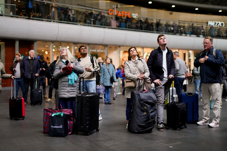 Passengers looking at the schedule board at London's King's Cross station