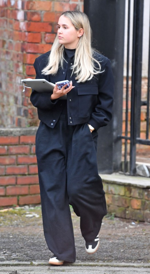 a woman wearing a black jacket and black pants is walking down the street