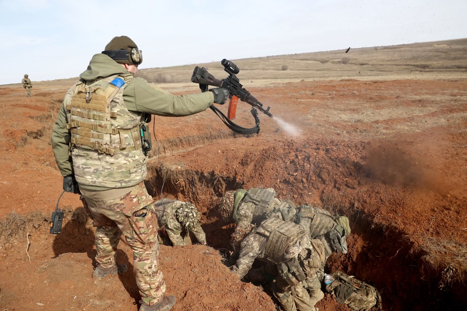 A Ukrainian army sergeant fires live rounds above the trainees to spur them on