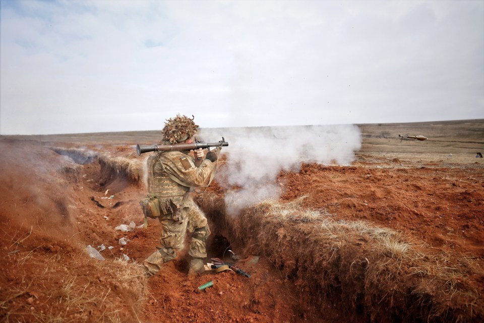 Amid a cloud of white smoke a soldier fires a rocket-propelled grenade