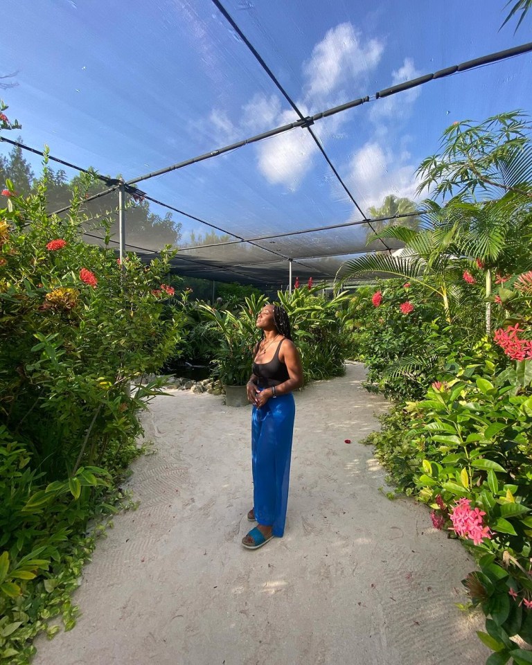 Posed in her lengthy goddess braids, attached with shiny hair braid rings, the star donned a simple black plunge vest tucked into deep blue beach kimono trousers