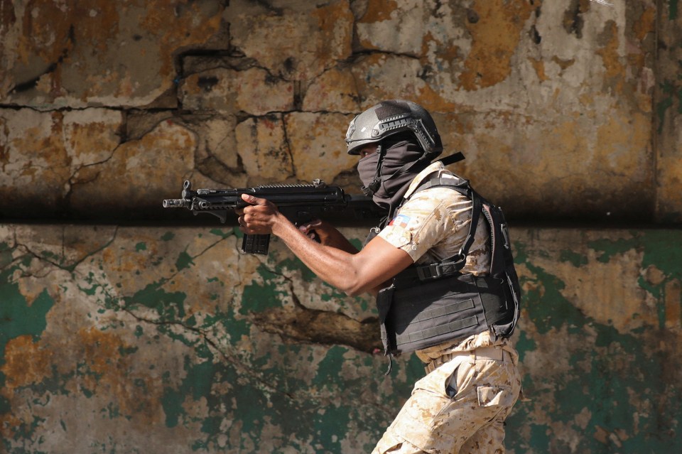 A police officer points his gun while confronting the gangs in the Port-au-Prince