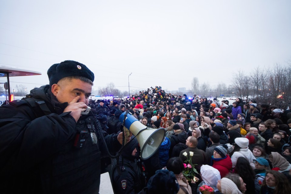 A police officer trying to control the massive crowd gathered to pay last tributes to Navalny