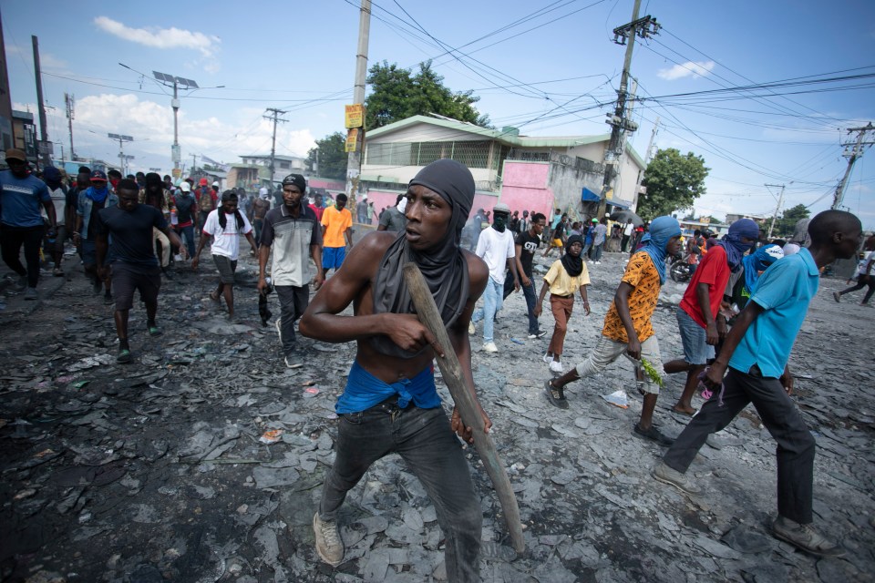 A protester carries a piece of wood simulating a weapon during a protest in Port-au-Prince