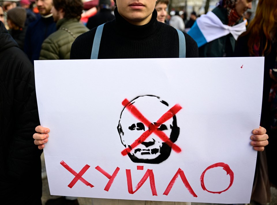 A protester holds a sign of a crossed-out Putin