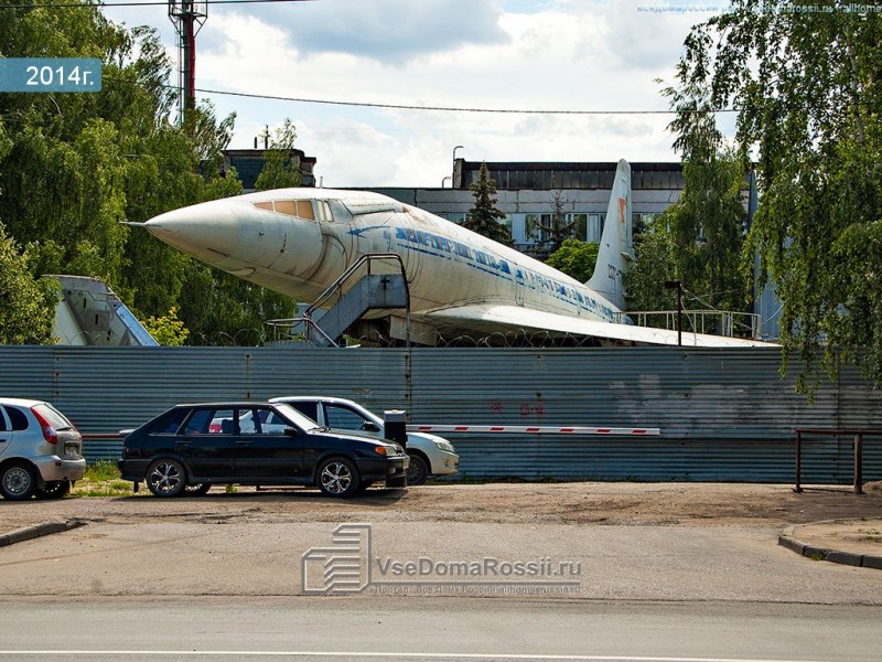 The nose of the air-craft pokes over the fence in the backyard of a military base