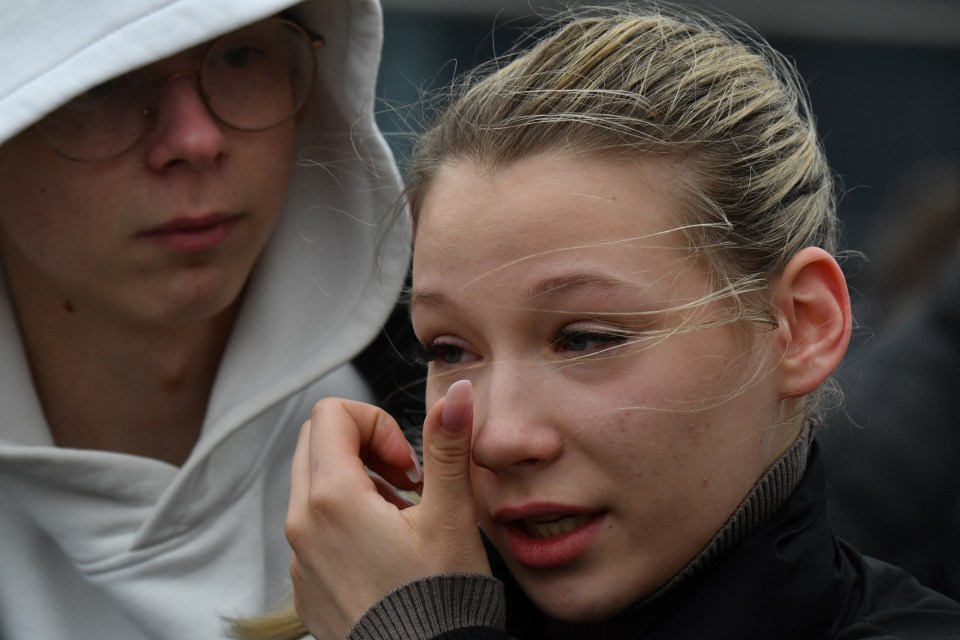 A Russian girl wipes away a tear as she visits a makeshift memorial