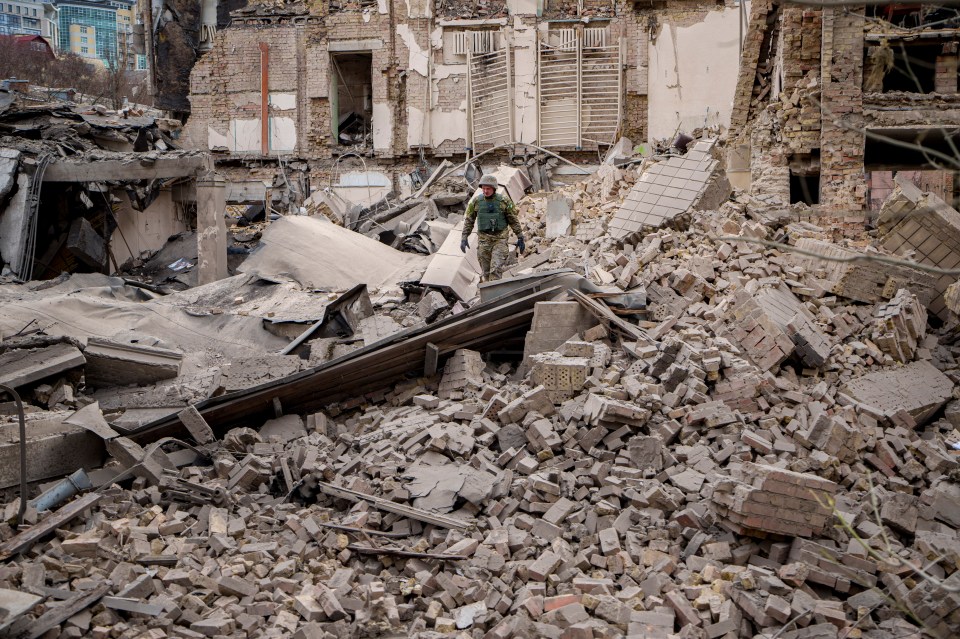 A Ukrainian serviceman inspects the damage to a building in the Pecherskyi district