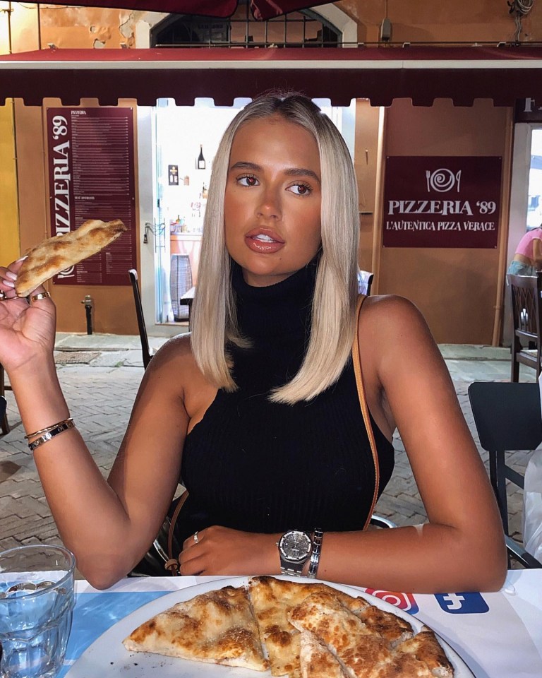 a woman eating pizza in front of a pizzeria 89 sign