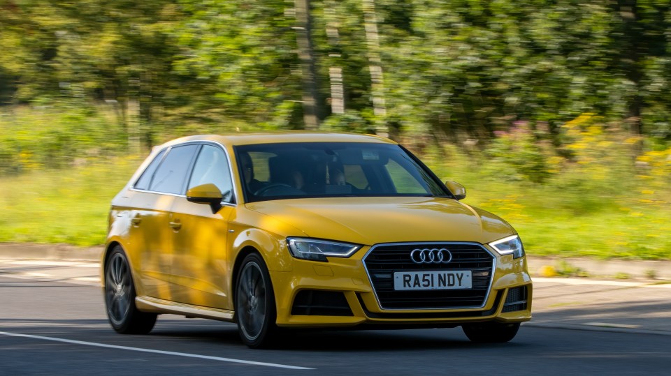 Yellow Audi A3 driving on a country road.