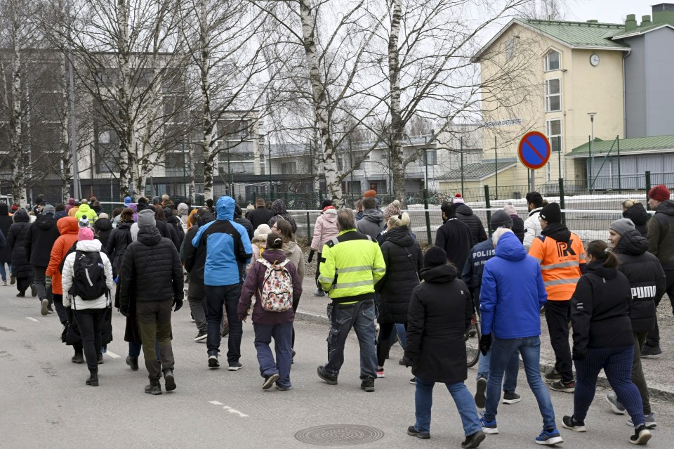 Family members of pupils gather outside the school