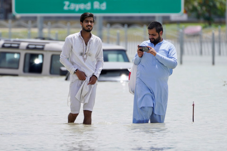 Two men walk through floodwater in Dubai on Wednesday