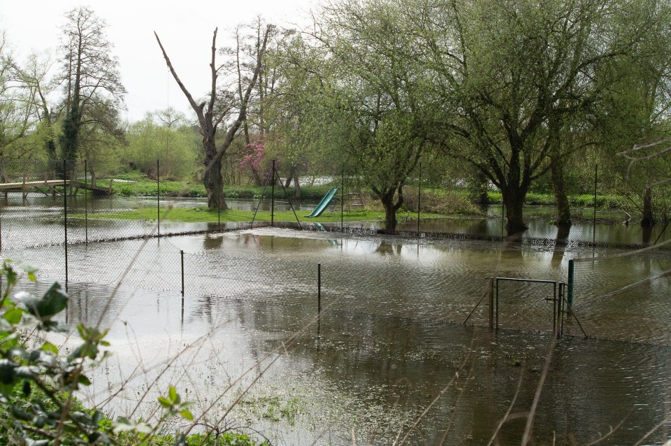 Flooding in a garden and tennis courts next to the Grand Union Canal towpath in Harefield, Uxbridge