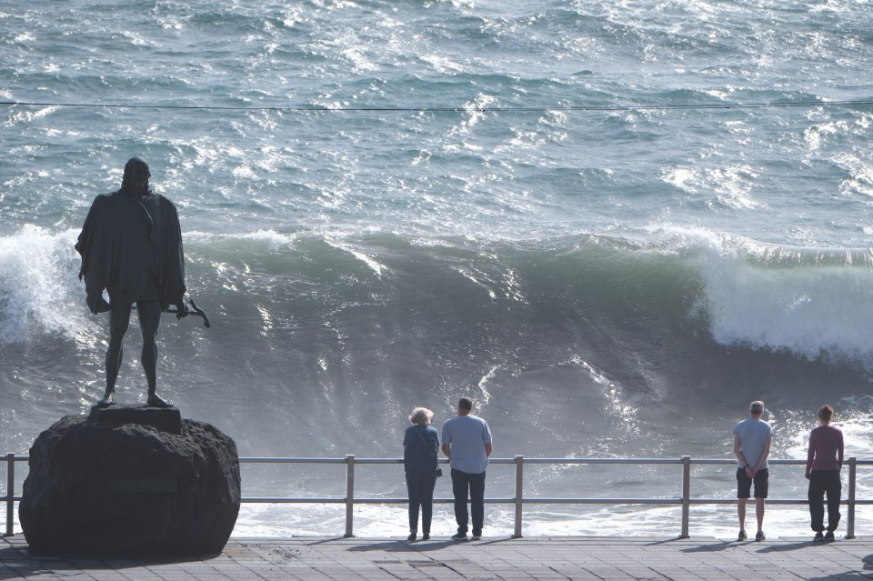 People look at the high waves breaking at Candelaria, Tenerife