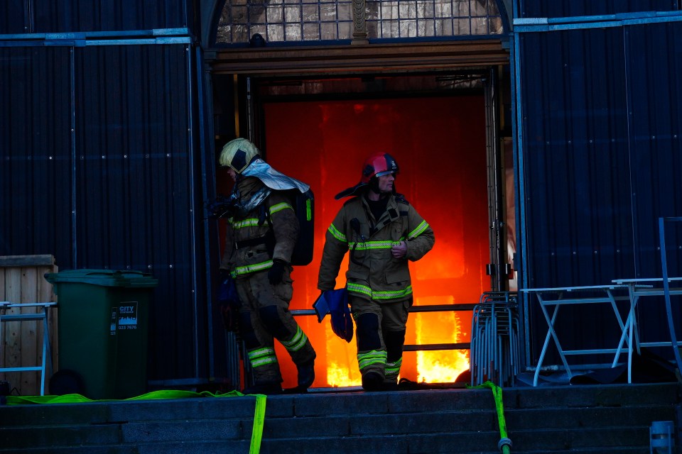 Firefighters walk out of the main entrance as the Old Stock Exchange burns