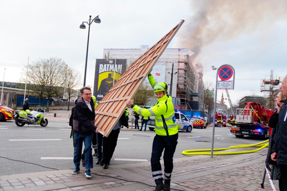 Locals helping to carry more paintings and other objects as a fire burns