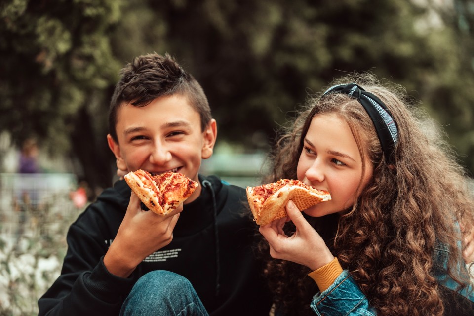 a boy and a girl on a lunch break at school. A meal in front of the school during a coronavirus pandemic. New normal. Selective focus. High quality photo