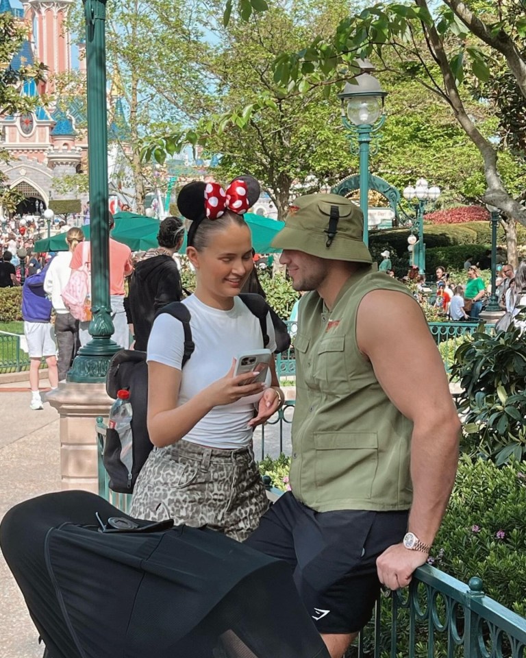 a woman wearing minnie mouse ears sits next to a man holding an umbrella