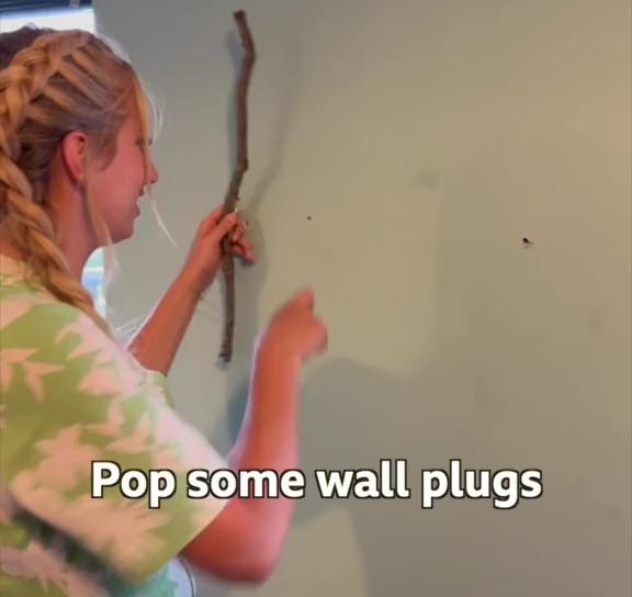 She then put wall plugs in the wall, before screwing the stick to it