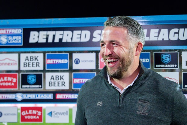 a man stands in front of a sign that says betfred super league