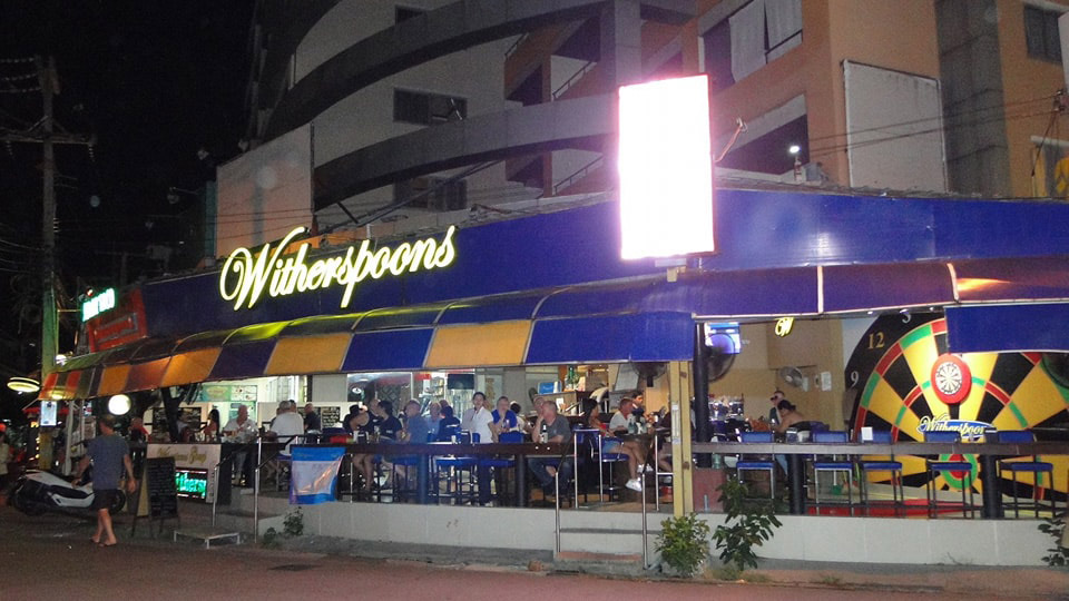 Customers gather in the outdoor seating at Witherspoons next to a giant dart board