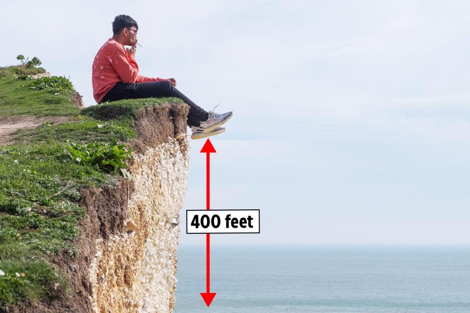 A smoker dangles his legs over the edge of a 400ft cliff, even though there are warnings about the fragile, soft chalk