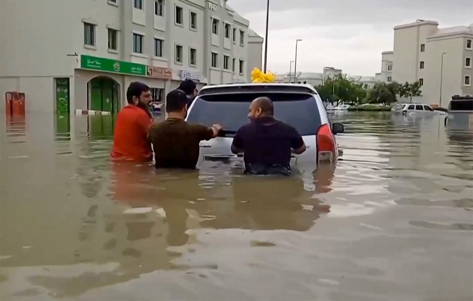 People have been seen pushing their cars to higher ground as they wade through water up to their waists