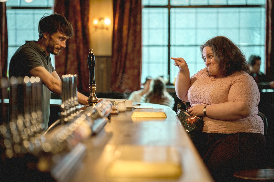 a woman sitting at a bar talking to a bartender