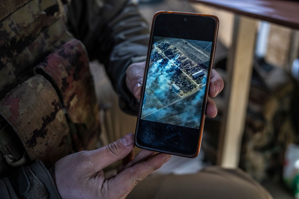 A soldier of a Ukrainian reconnaissance drone unit shows a photograph of a previous successful strike on Russian forces at a position in Donbas