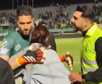 The Iranian footballer can be seen briefly embracing the supporter as a security guard nags him about it