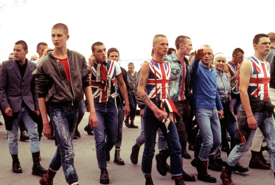 A group of skinheads on a march as one performs a Nazi salute