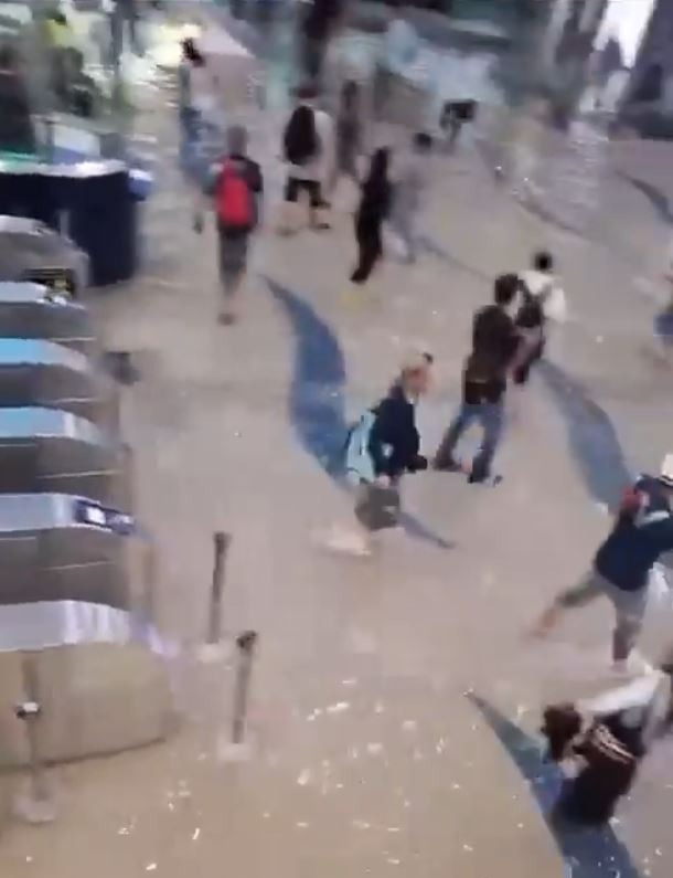 Travellers wade through ankle-deep water in a flooded metro station