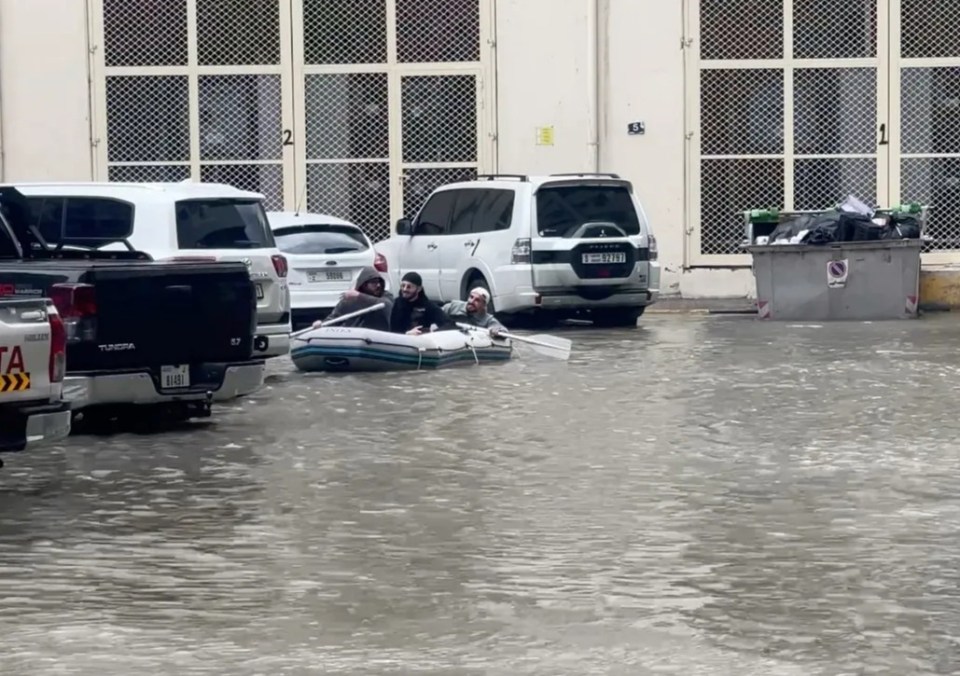 A group of men sail on a boat on a flooded street in Dubai