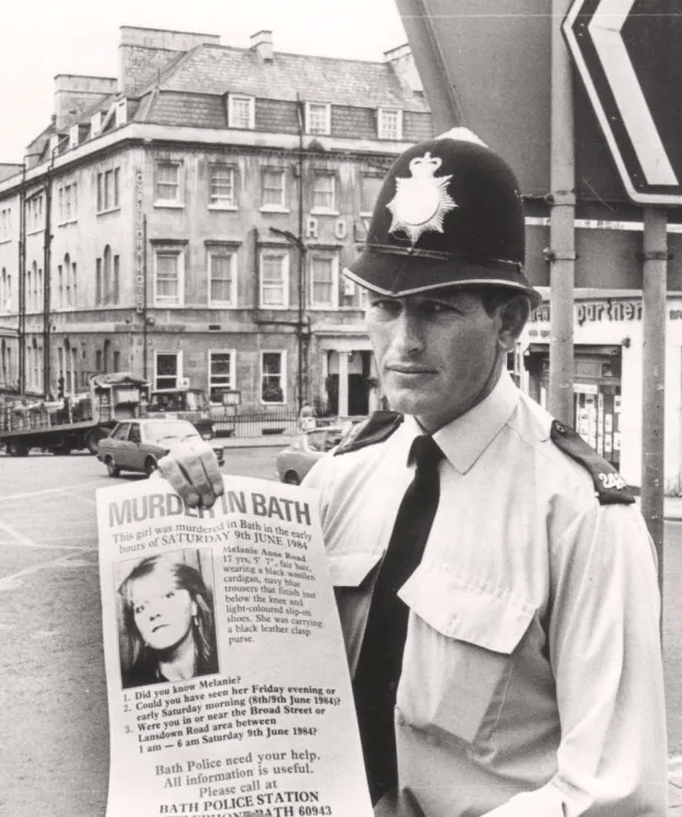 A policeman holds a poster appealing for help in the hunt for the killer of the teen