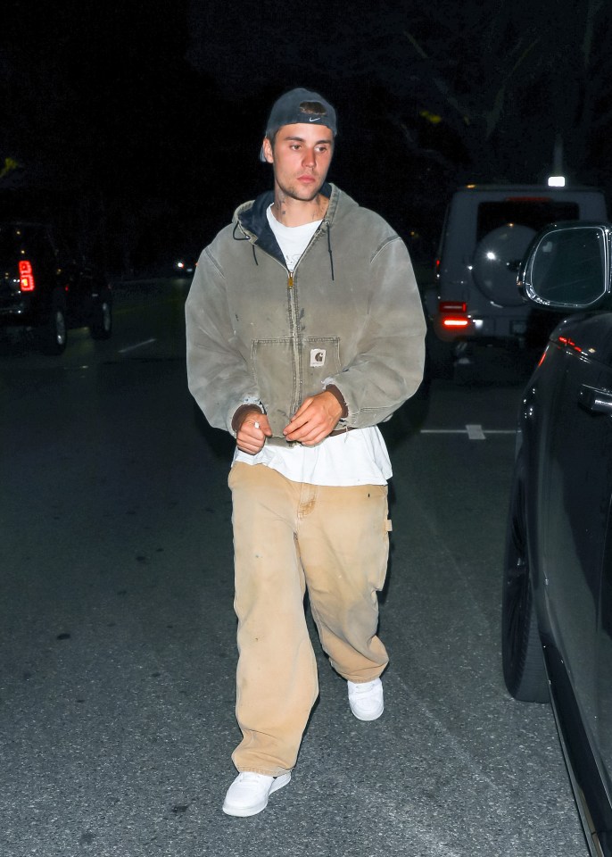 a man wearing a carhartt jacket stands in a parking lot