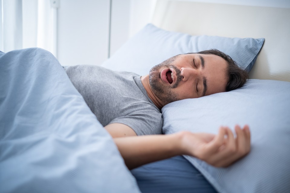 Man snoring loudly in his bed while sleeping