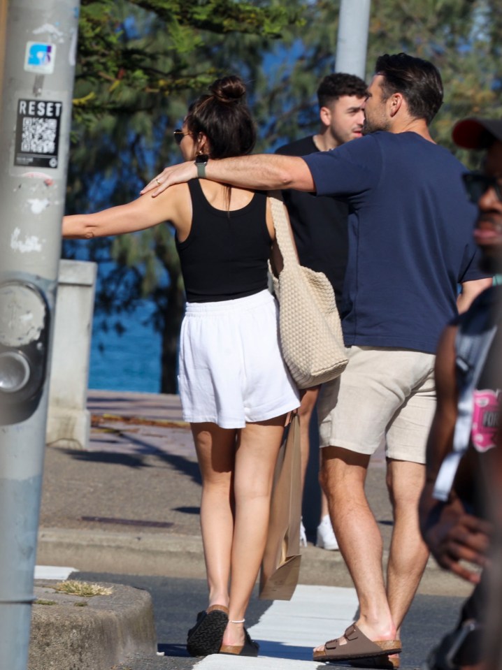 Mark walks with his arm over Michelle after they packed on the PDA while sunbathing